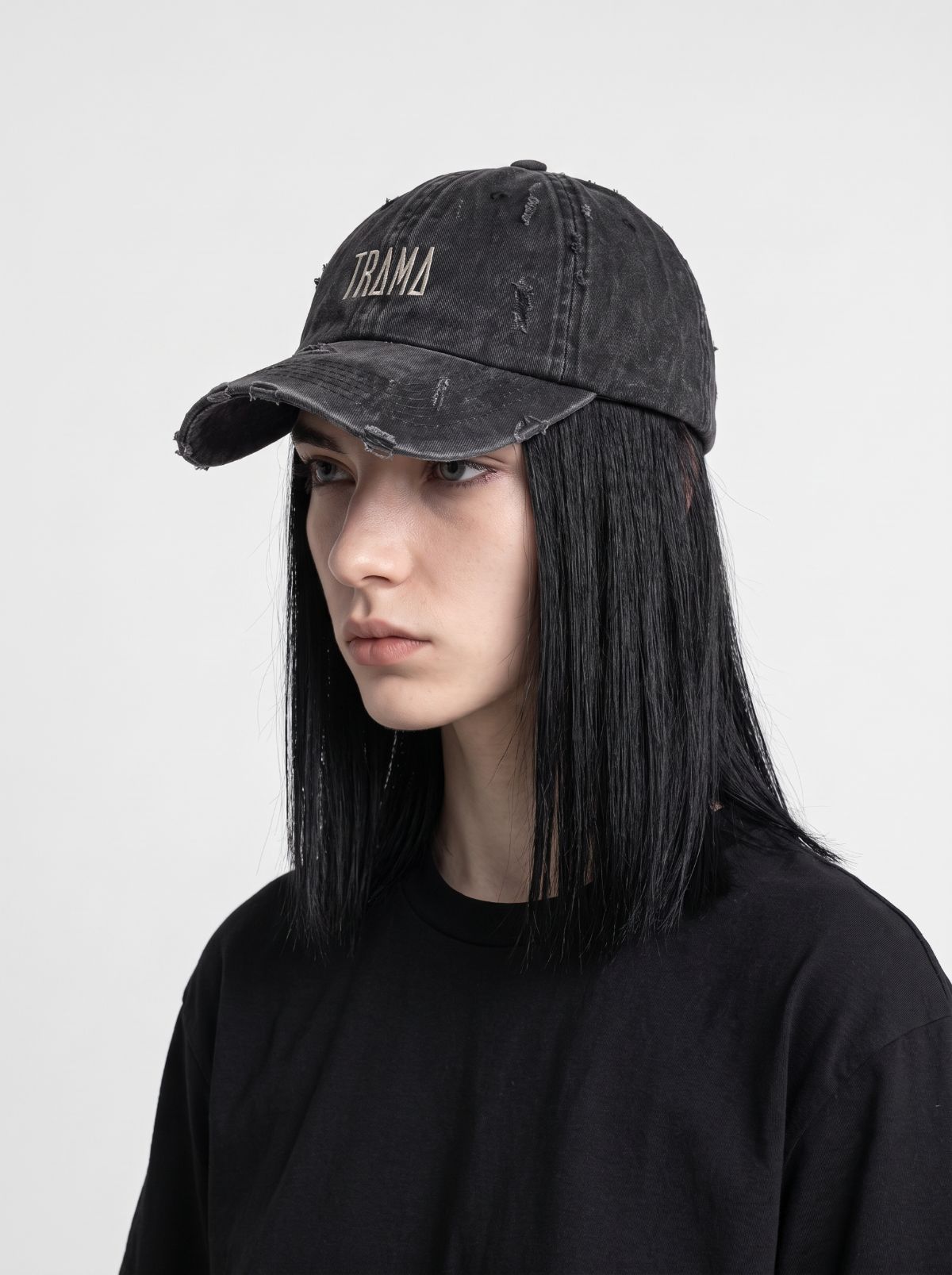 Modelo con gorra Trama negra lavada y desgastada, bordado gris y visera deshilachada