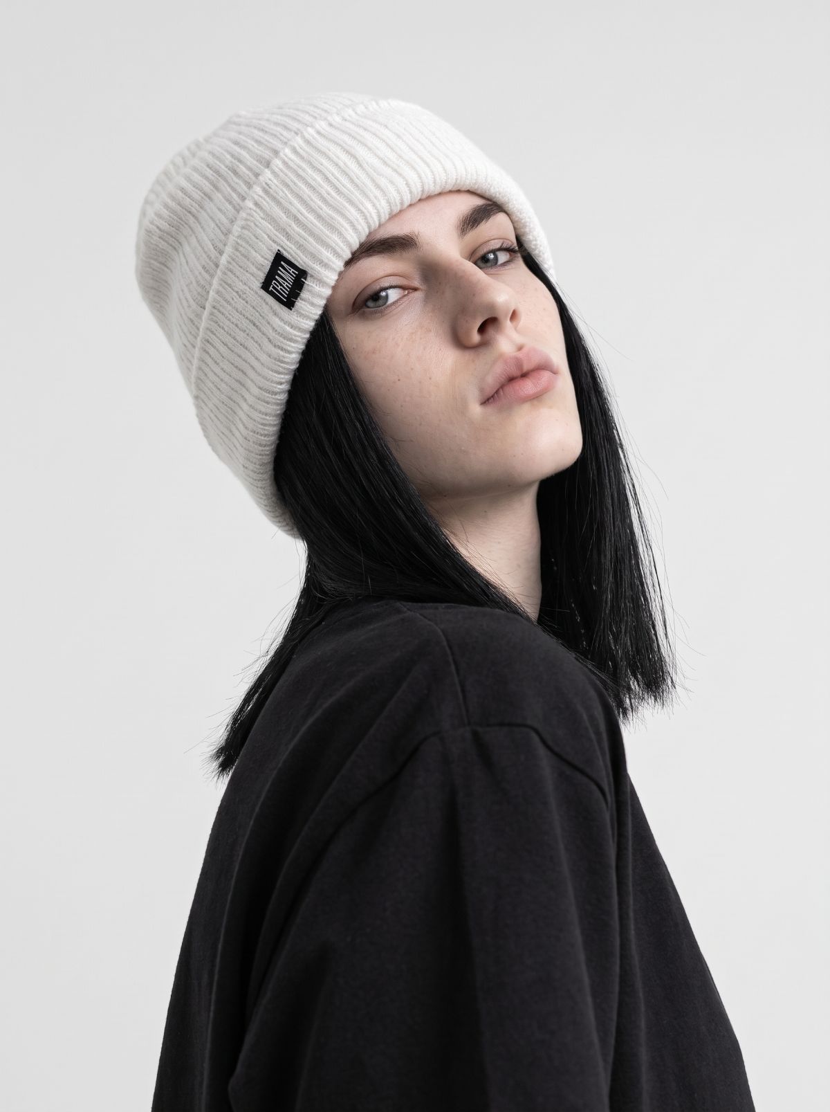 Modelo con gorro Trama blanco de lana acanalada y etiqueta negra con la marca